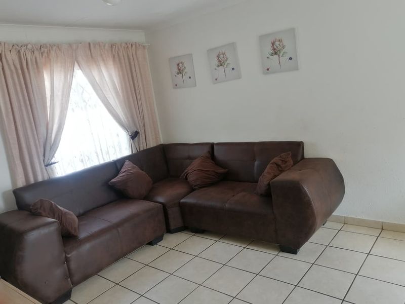 A living room area featuring neutral tiled flooring and window curtain rails, providing a functional and well-lit space.