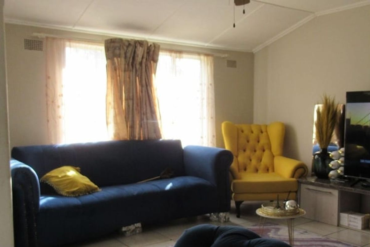 A living room featuring tiled flooring, a ceiling fan, and a wall-mounted air conditioning unit.