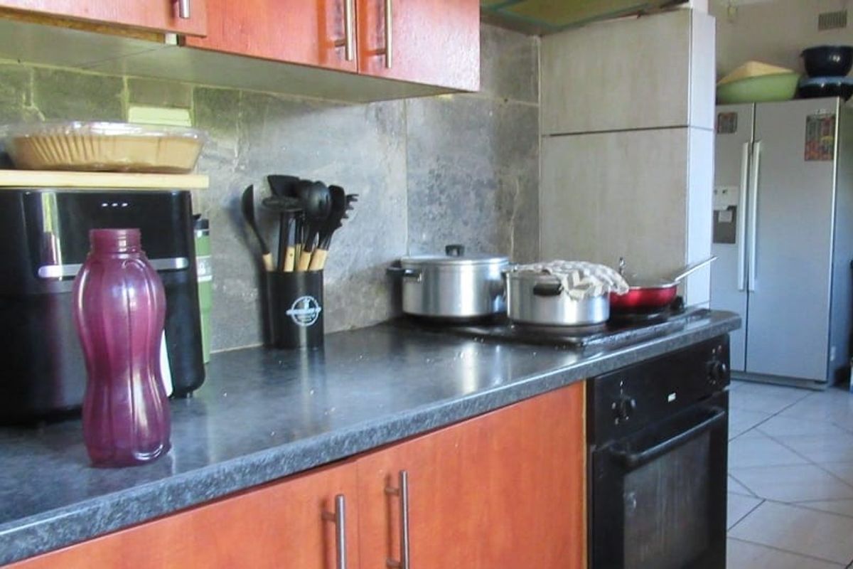 A functional kitchen featuring wood-look cabinetry, stone tile backsplash, and built-in oven with electric hob, requiring cosmetic updates to modernize the space.
