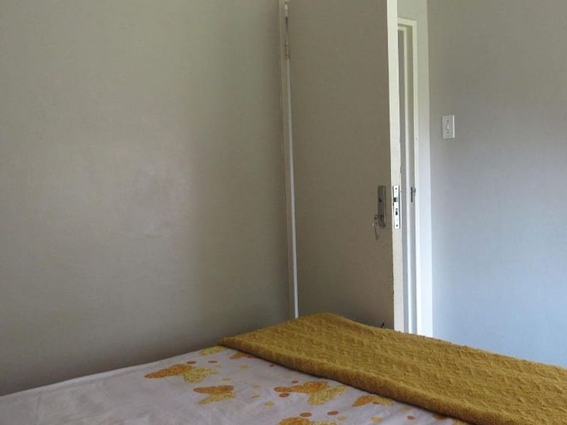 A simple bedroom interior featuring neutral walls and a standard doorway.