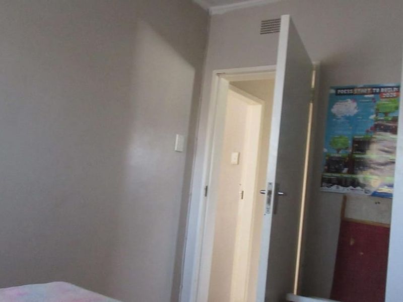 A simple bedroom interior featuring a standard internal door and ventilation grille, presenting a blank canvas for potential renovation or restyling.