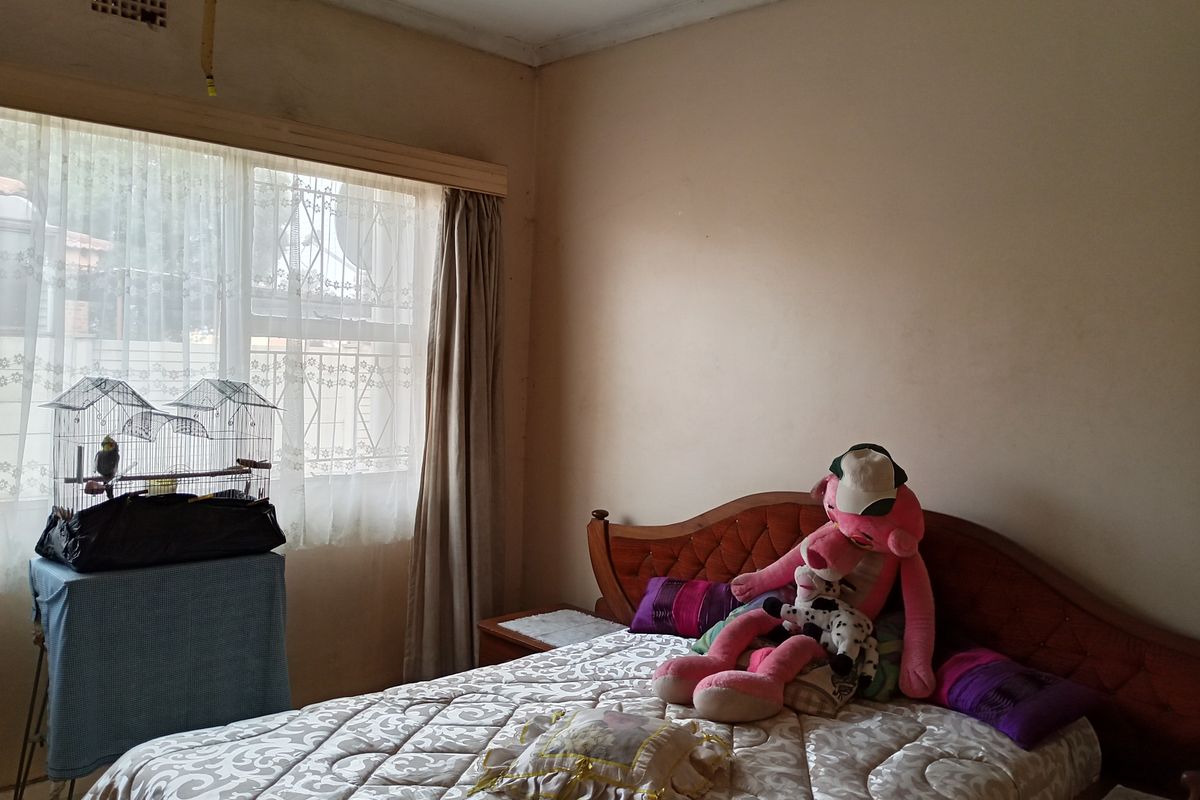 A bedroom featuring a window with curtains and a neutral wall finish, requiring cosmetic updates to improve the overall aesthetic.