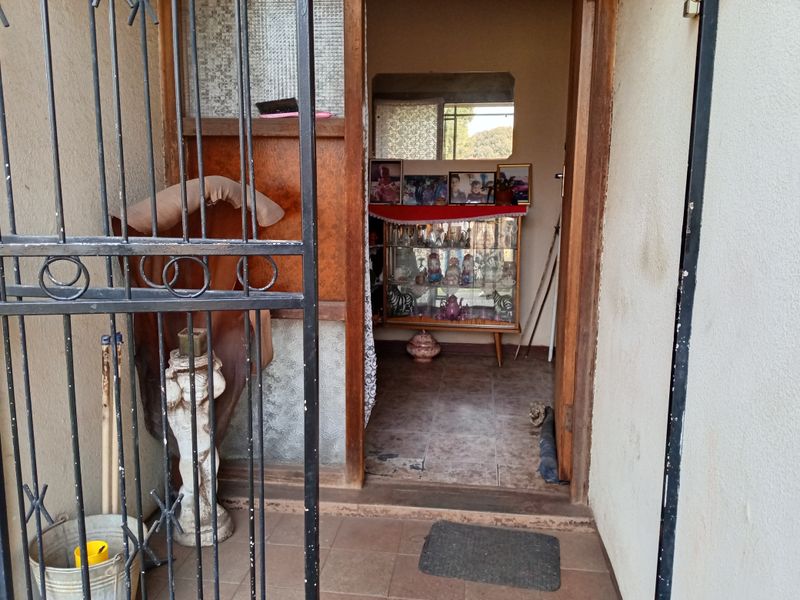 Entrance area featuring a security gate, tiled flooring, and a wooden door frame leading into the home interior.