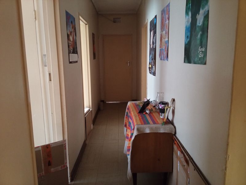 A functional residential hallway featuring tiled flooring and multiple internal door access points, requiring cosmetic updates to improve its overall appearance.