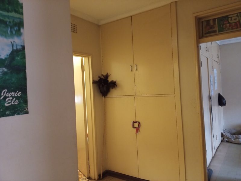 A hallway featuring built-in storage cupboards and access to adjacent rooms.