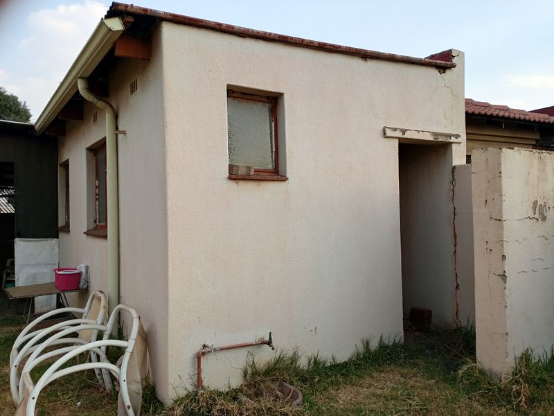 A detached utility structure showing significant signs of wear, including wall cracking and weathered exterior finishes, requiring maintenance and repair.