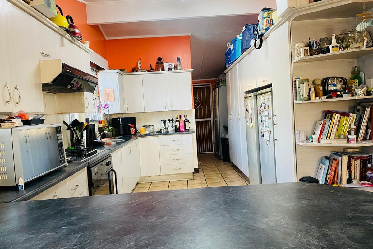 A functional kitchen featuring white cabinetry, dark countertops, built-in oven and hob, and tiled flooring, offering ample storage and workspace.