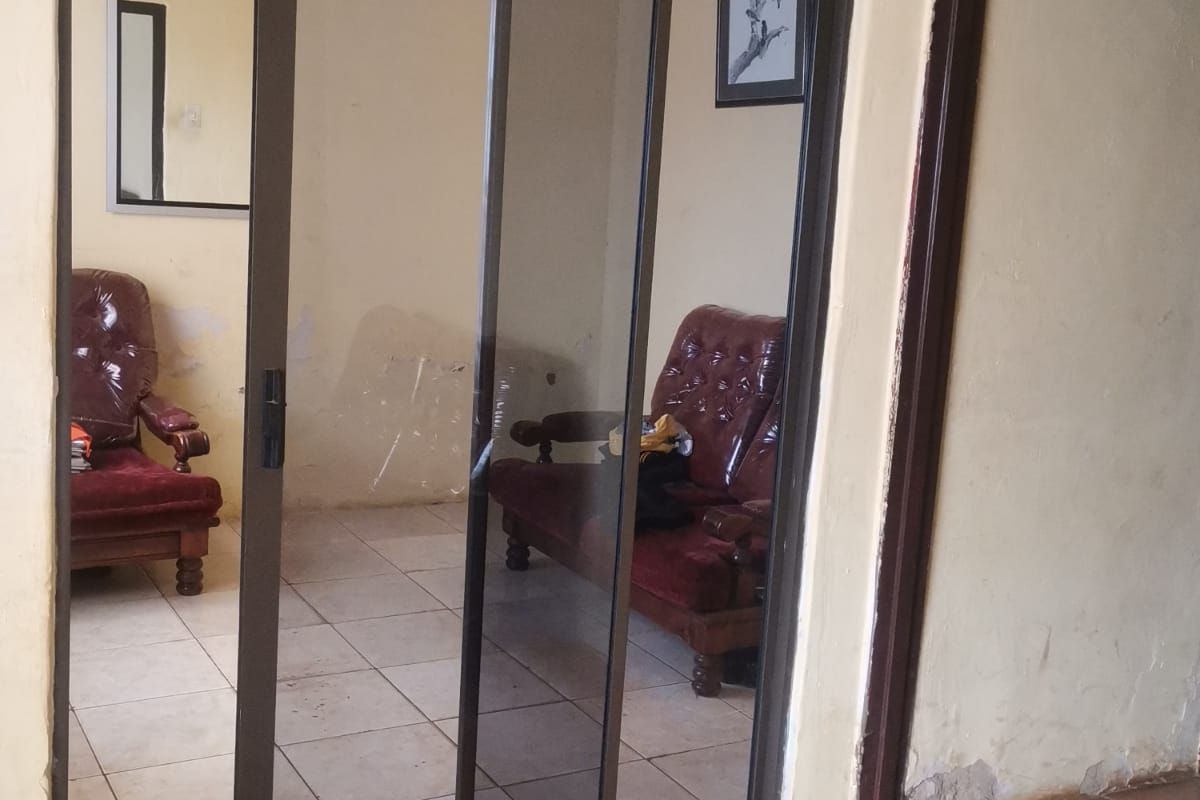 Living area featuring a sliding glass door, tiled flooring, and visible wall plaster damage requiring maintenance and cosmetic updates.
