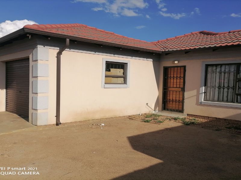 Front elevation of a single-story house featuring a double garage, tiled roof, and security features including burglar bars and a security gate.