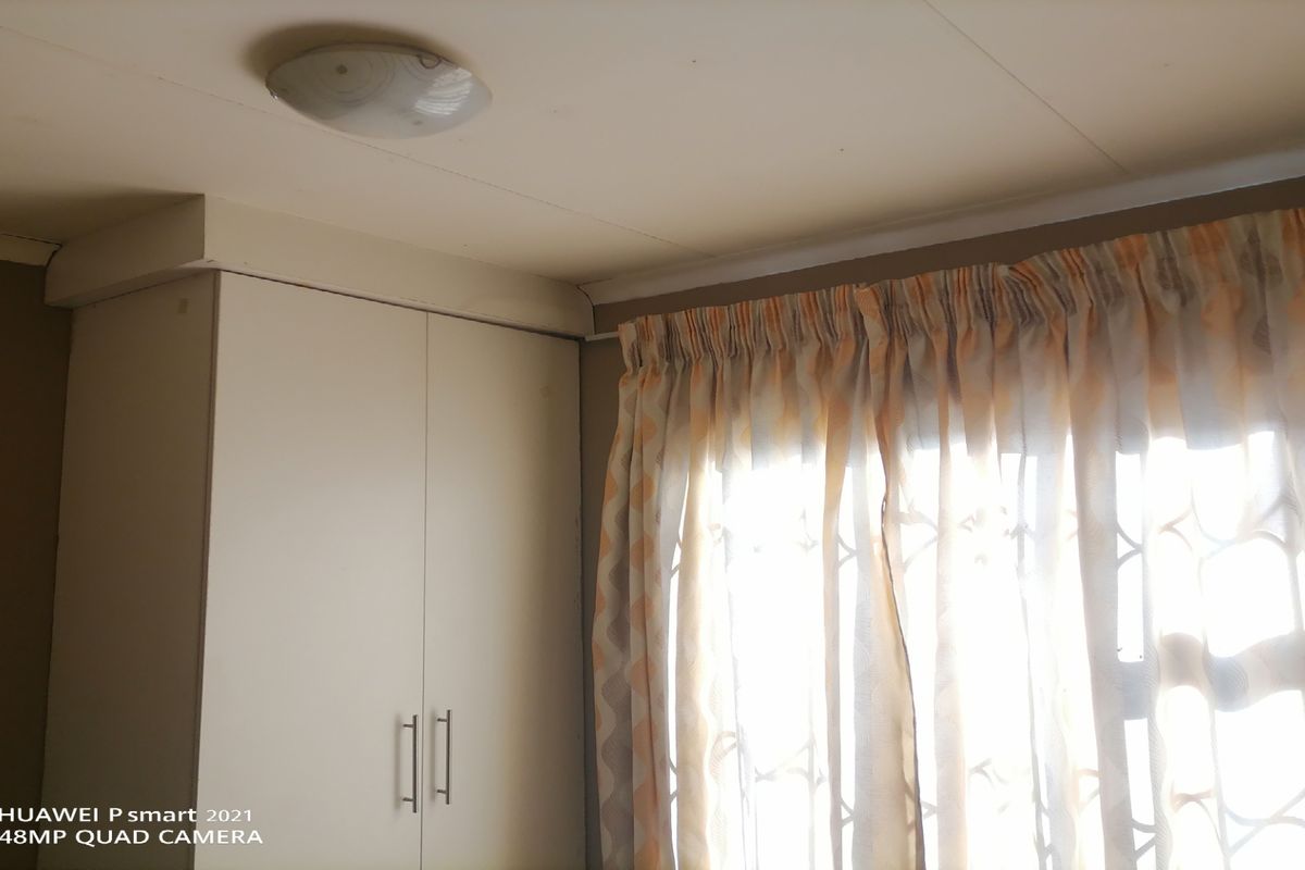 A bedroom interior featuring a built-in wardrobe and a window fitted with a security gate.