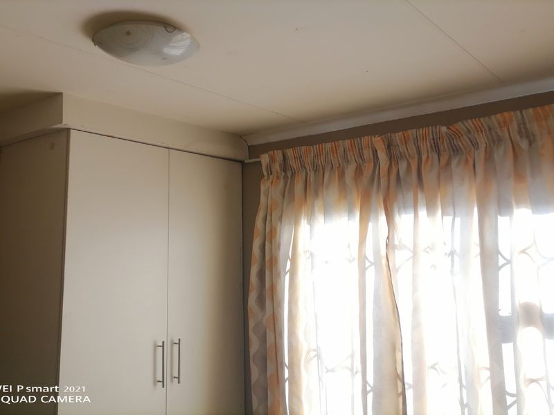 A bedroom interior featuring a built-in wardrobe and a window fitted with a security gate.