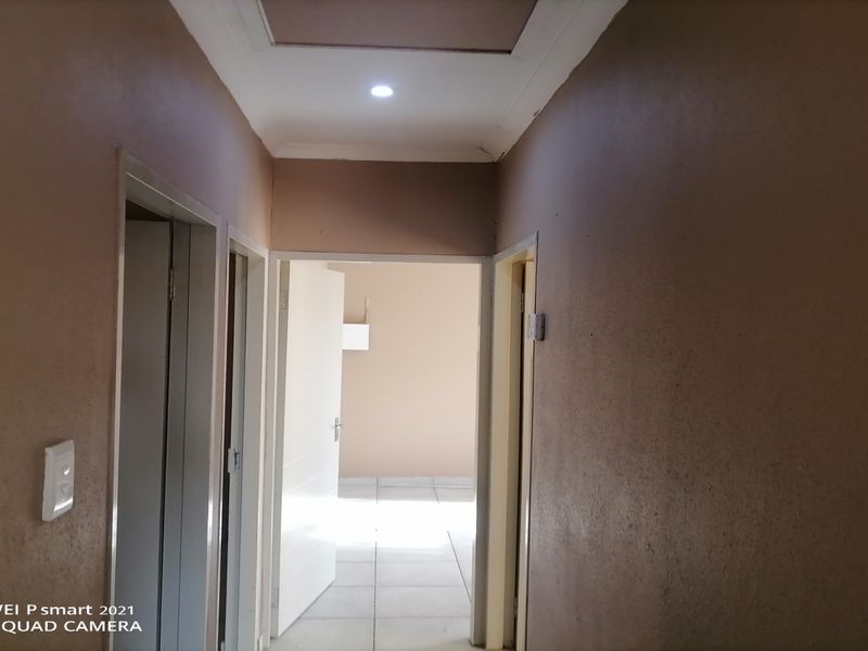 A functional hallway featuring tiled flooring, recessed lighting, and access to multiple rooms through internal doorways.