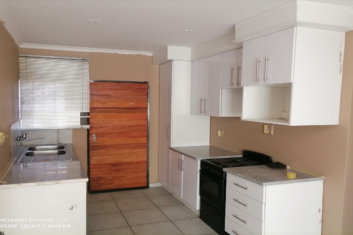 A functional kitchen featuring white cabinetry, a double sink, and an electric stove, with tiled flooring and neutral wall tones.