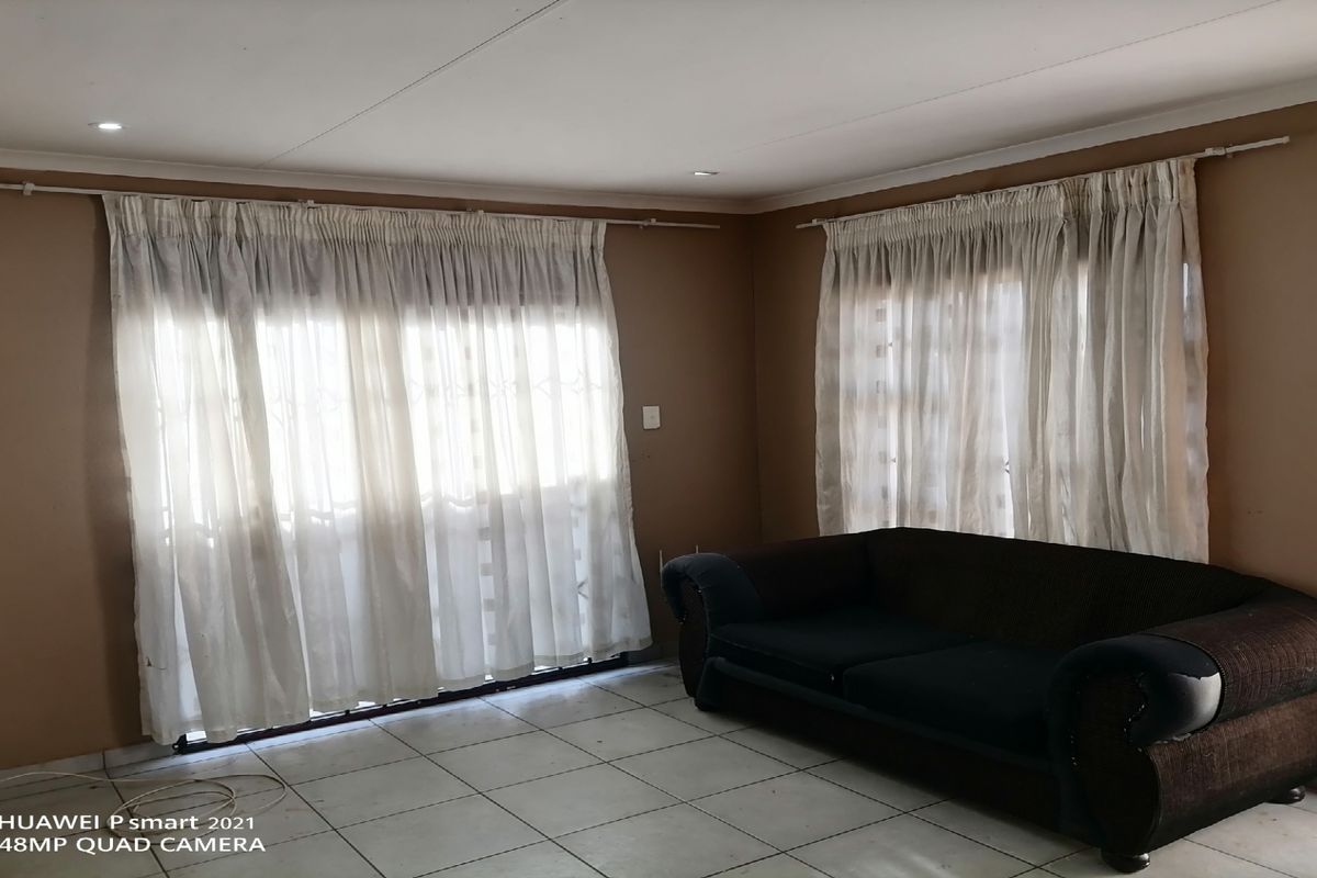 A living room featuring tiled flooring, recessed downlights, and large windows with security gates and curtain rails.