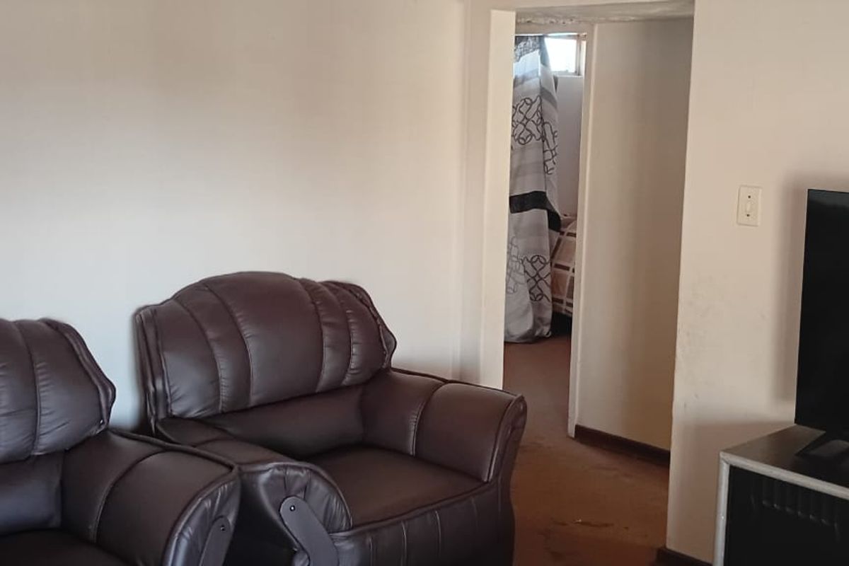 A living room area featuring plain walls and worn flooring, providing a basic foundation for potential interior updates and modernization.