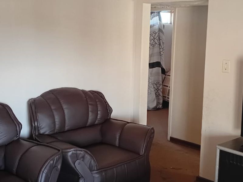 A living room area featuring plain walls and worn flooring, providing a basic foundation for potential interior updates and modernization.