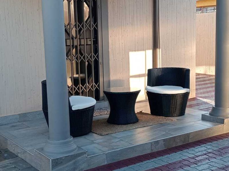 A covered patio area featuring decorative columns, tiled flooring, and a secure metal entrance gate.