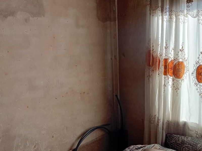 A bedroom interior showing significant wall surface wear and staining, requiring cosmetic repair and refurbishment.