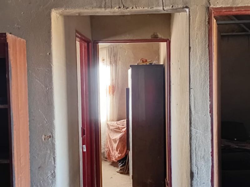 A view through a hallway showing multiple doorways with visible plaster damage and signs of significant wear on the wall surfaces.