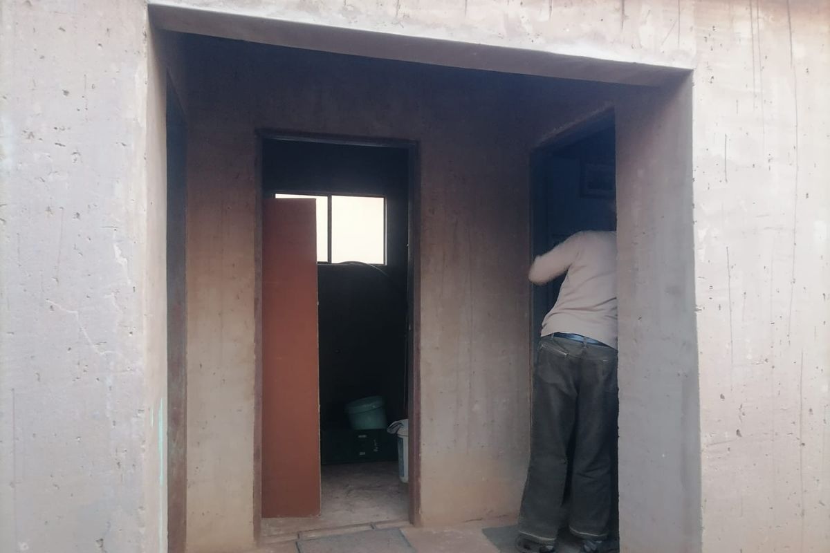 An interior hallway area featuring unfinished concrete walls and door frames, currently in a shell condition awaiting final finishes.