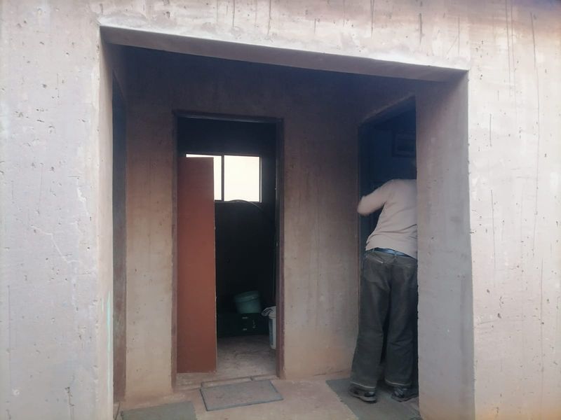 An interior hallway area featuring unfinished concrete walls and door frames, currently in a shell condition awaiting final finishes.