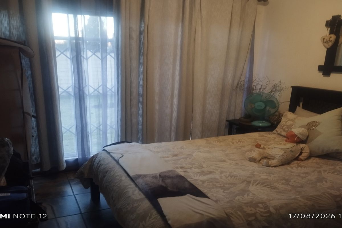 A bedroom featuring tiled flooring and a sliding door with security gate access to the exterior.