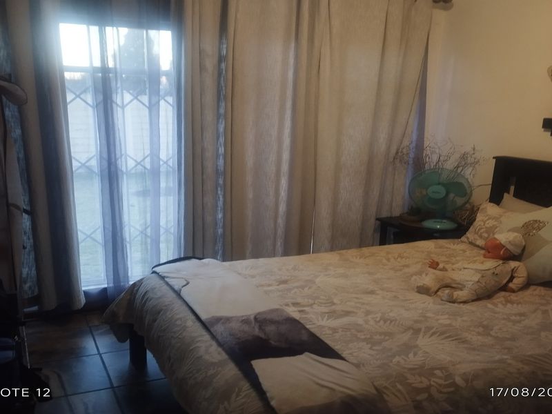 A bedroom featuring tiled flooring and a sliding door with security gate access to the exterior.