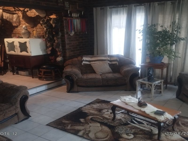 A living room featuring exposed brick walls and tiled flooring, offering a rustic aesthetic with natural light from large windows.