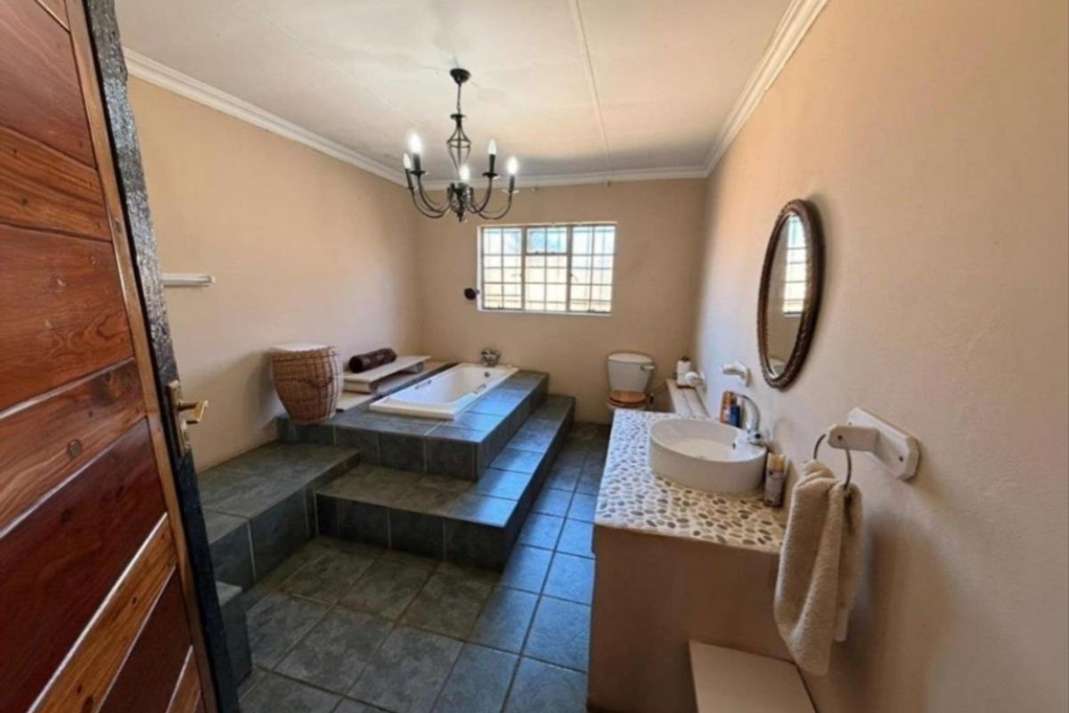 Spacious bathroom featuring a raised tiled bathtub platform, vessel sink vanity, and classic chandelier lighting.