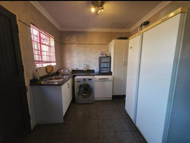 A functional laundry room featuring tiled walls and floors, granite countertops, built-in cabinetry, and dedicated space for laundry appliances.