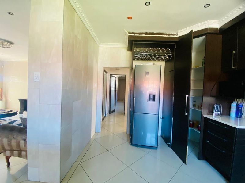 Kitchen area featuring tiled flooring, built-in cabinetry, and a dedicated pantry space, with some minor finishing work required on the bulkhead.