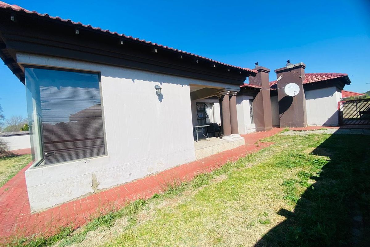 Rear view of the property featuring a covered patio, tiled roof, and a brick-paved walkway leading along the exterior wall.