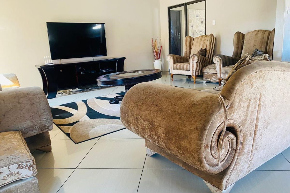 A spacious living room featuring neutral tiled flooring and a sliding glass door, providing a functional and well-lit area for relaxation.