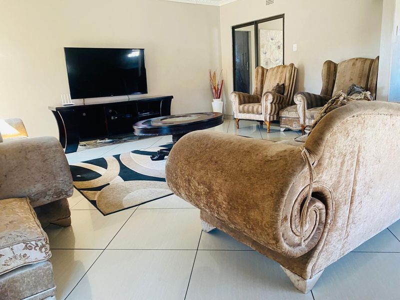 A spacious living room featuring neutral tiled flooring and a sliding glass door, providing a functional and well-lit area for relaxation.