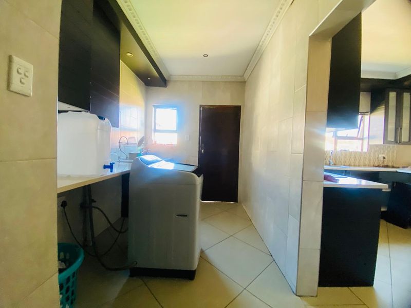 A functional laundry area featuring tiled flooring, built-in cabinetry, and dedicated plumbing connections, providing a practical space for household utility tasks.
