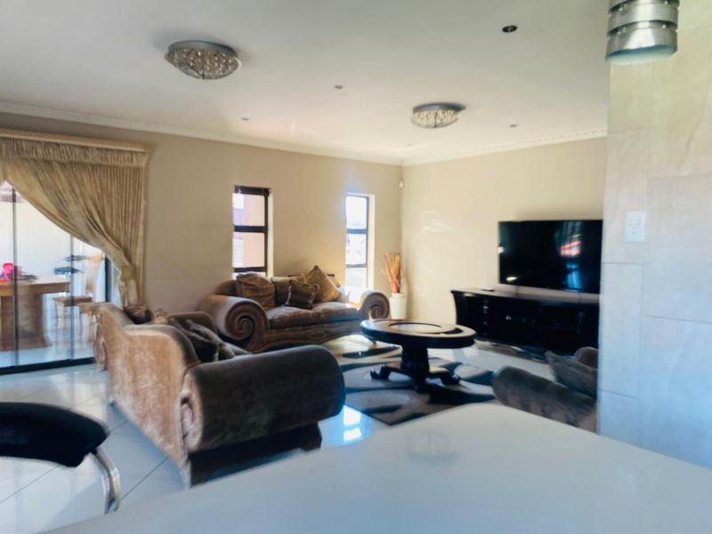 Spacious living room featuring tiled flooring, recessed downlights, and a sliding glass door providing access to the outdoor area.