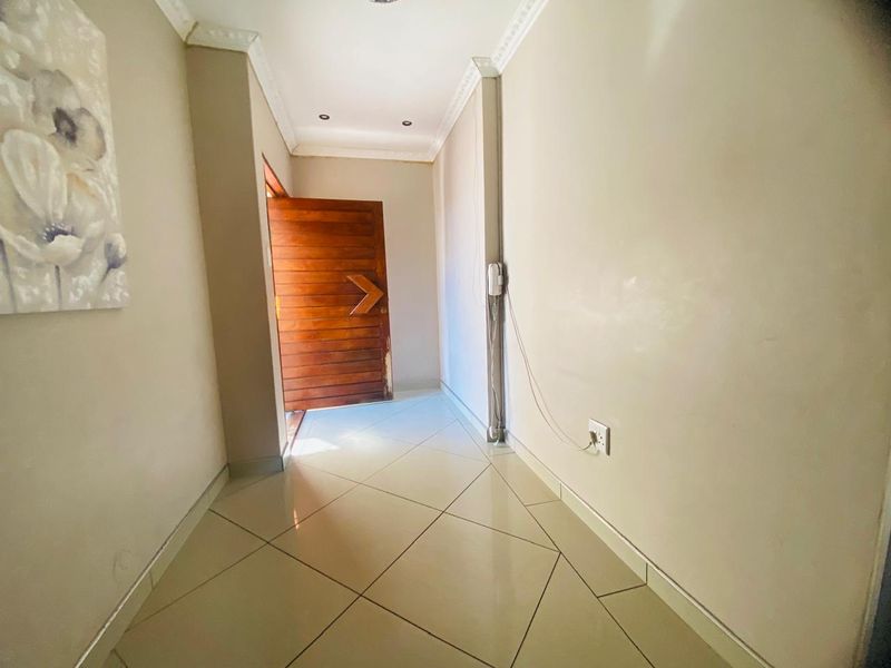 A bright entrance hall featuring tiled flooring, decorative cornicing, and a solid timber front door, providing a clean and welcoming transition into the home.