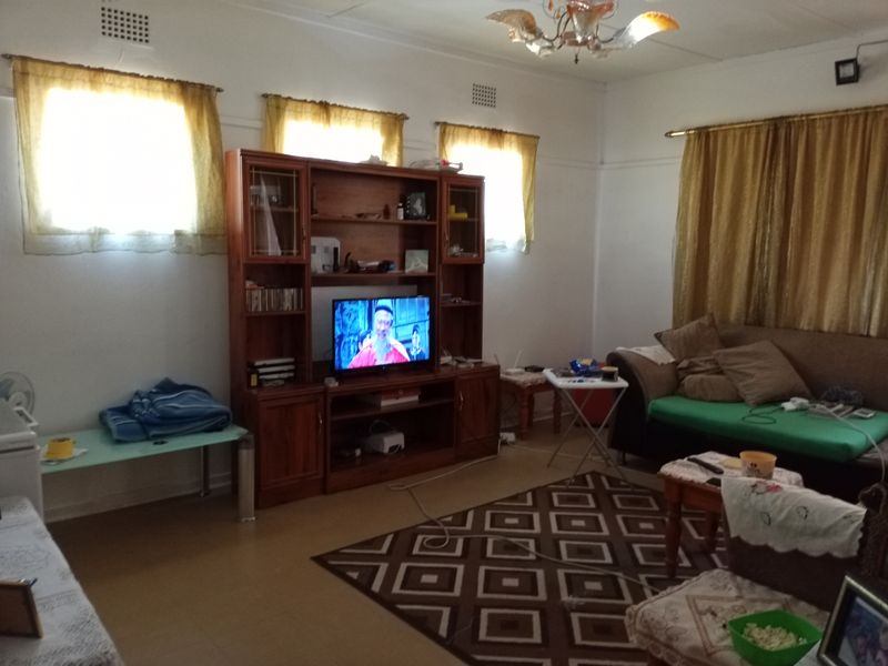 A living room featuring tiled flooring and ceiling ventilation, providing a functional space for relaxation.