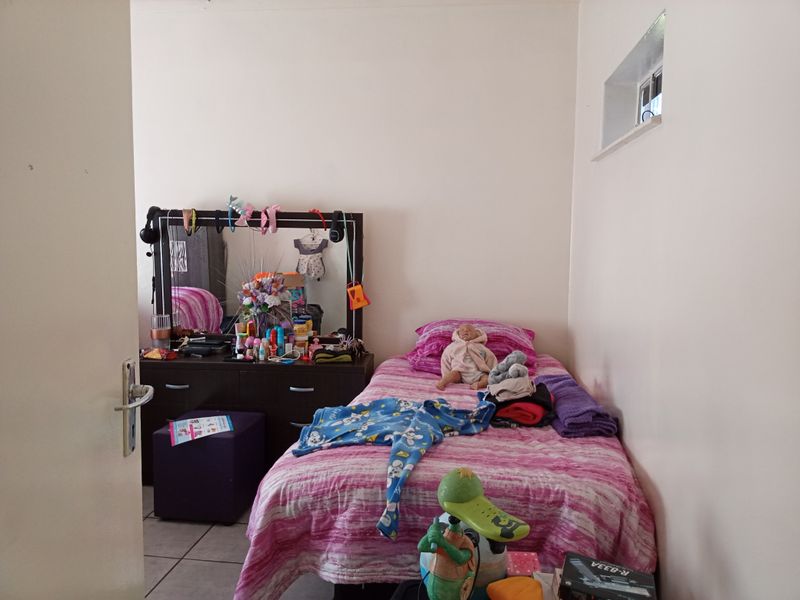 A functional bedroom featuring tiled flooring and a high-level window, providing natural light and a simple layout.