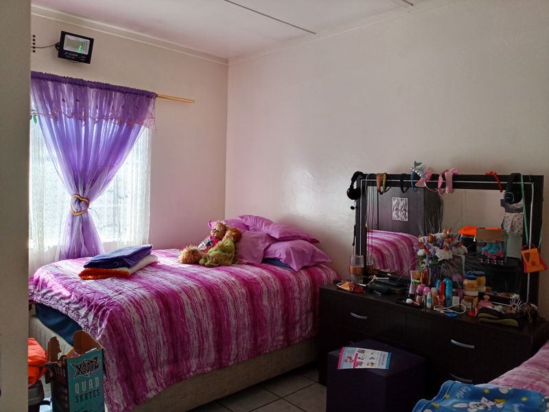 A standard bedroom featuring tiled flooring and a window fitted with a security gate.