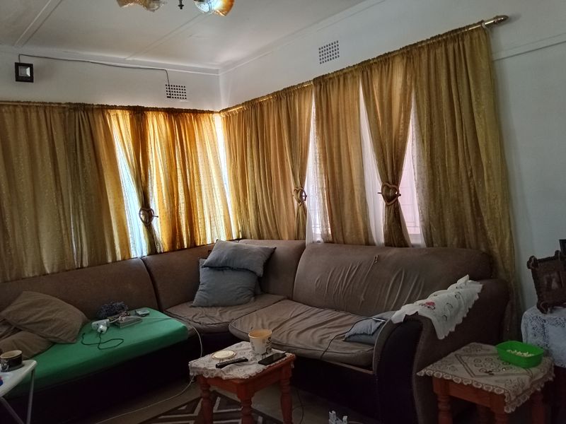 A living room area featuring large windows with floor-to-ceiling curtains and standard ceiling finishes.