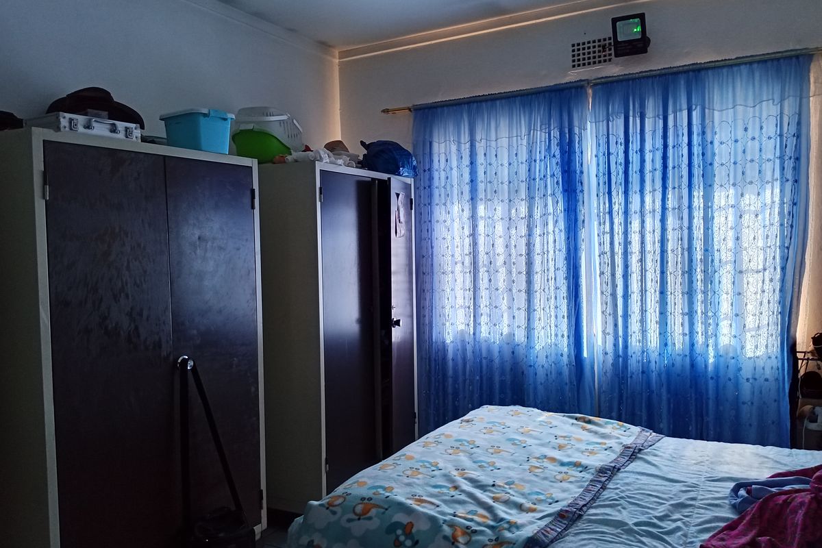 A functional bedroom featuring built-in cupboards and a ventilation grille, providing basic storage and ventilation.