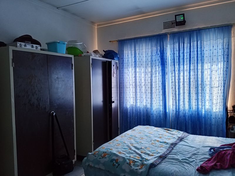 A functional bedroom featuring built-in cupboards and a ventilation grille, providing basic storage and ventilation.