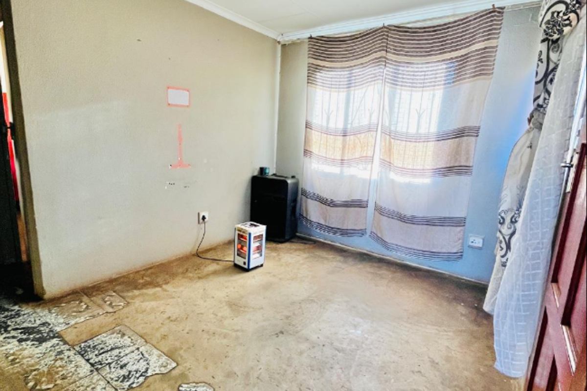 An empty bedroom featuring worn flooring and plain walls, offering a blank canvas for renovation and interior design updates.