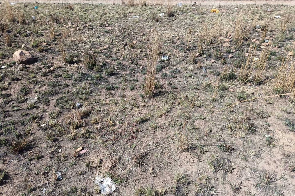 A view of an undeveloped residential plot featuring natural dry grass and uneven terrain.