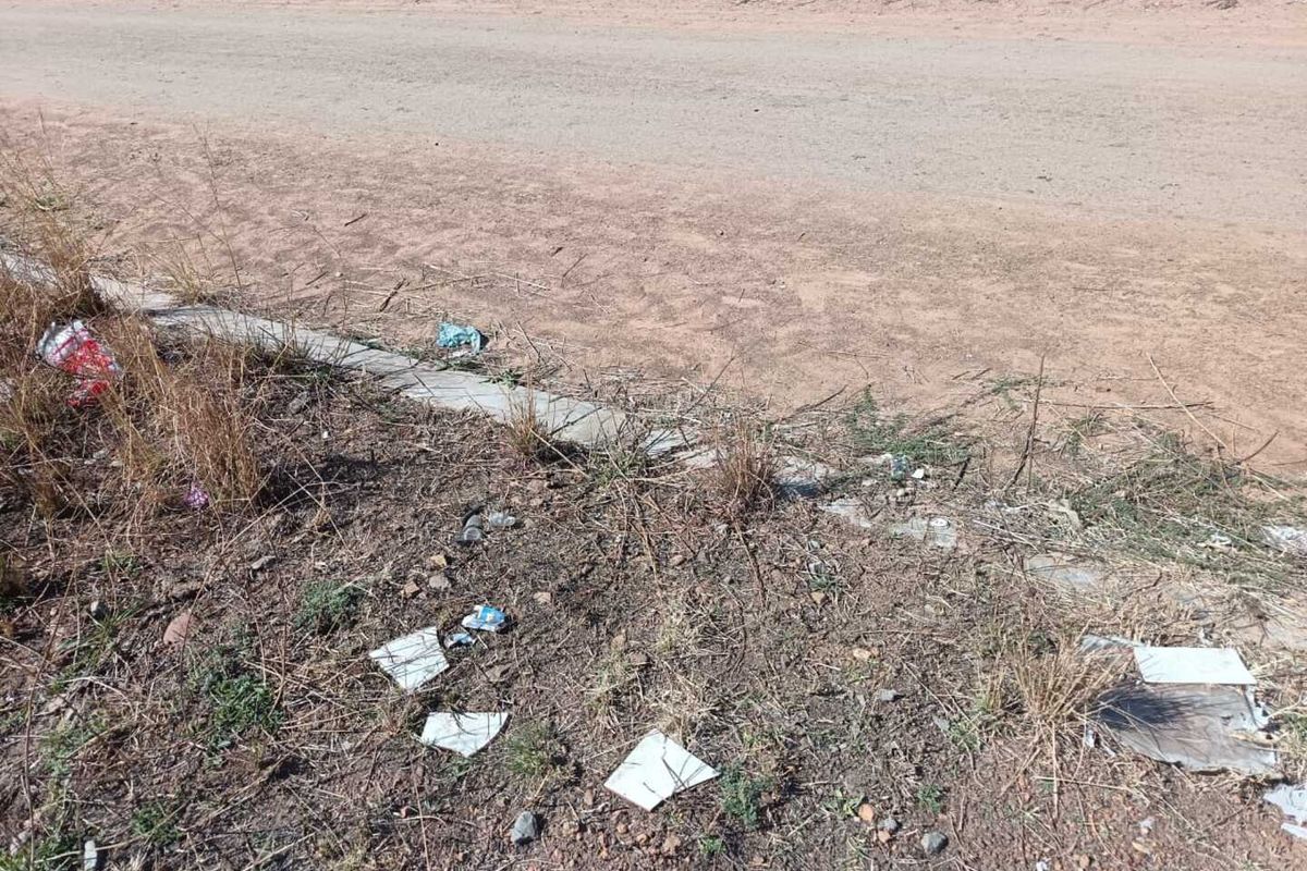 A view of the unpaved road frontage and concrete curb bordering the vacant residential land.
