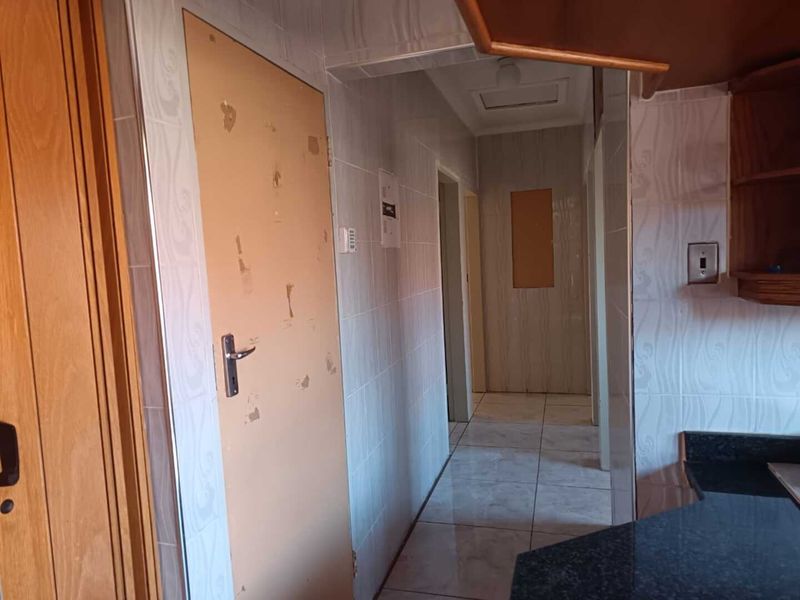A tiled hallway featuring a worn interior door and access to adjacent living spaces with granite countertop surfaces visible.