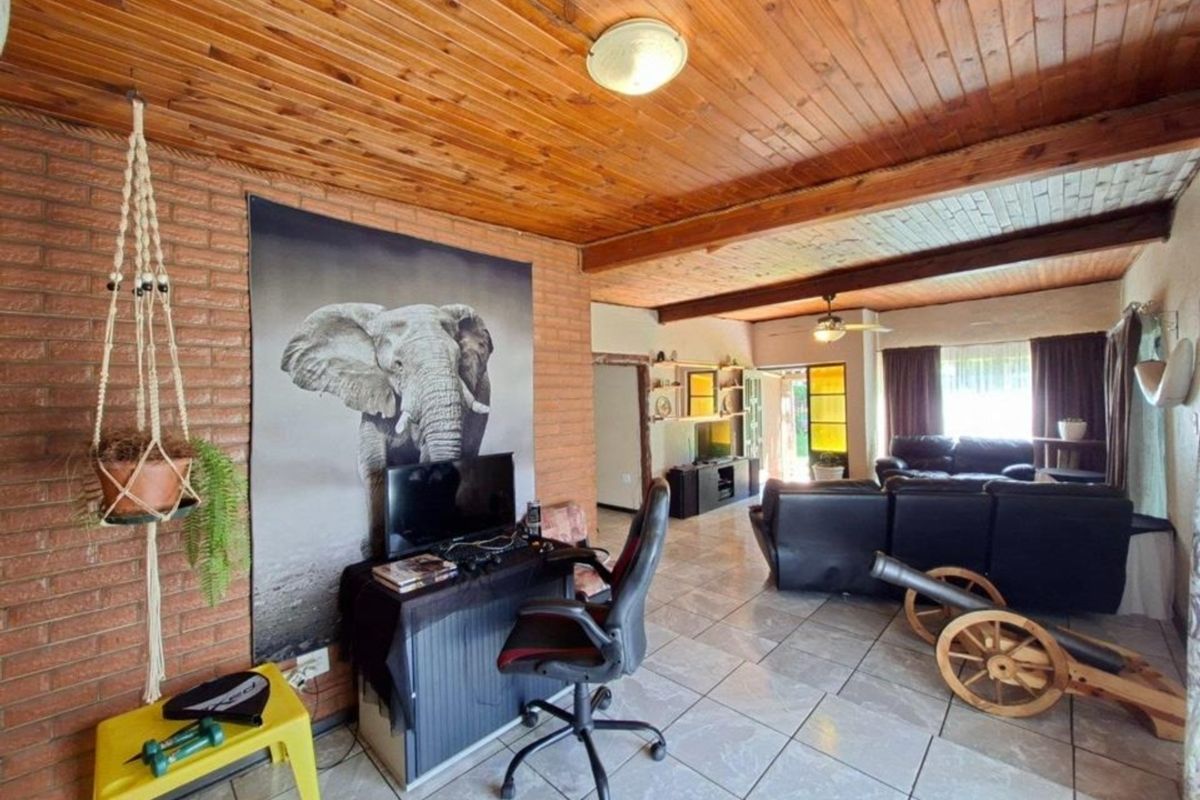 Spacious living area featuring exposed brick walls, a warm timber tongue and groove ceiling, and neutral ceramic floor tiles throughout.