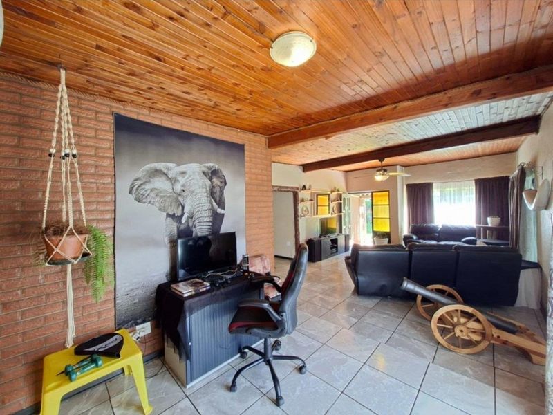 Spacious living area featuring exposed brick walls, a warm timber tongue and groove ceiling, and neutral ceramic floor tiles throughout.