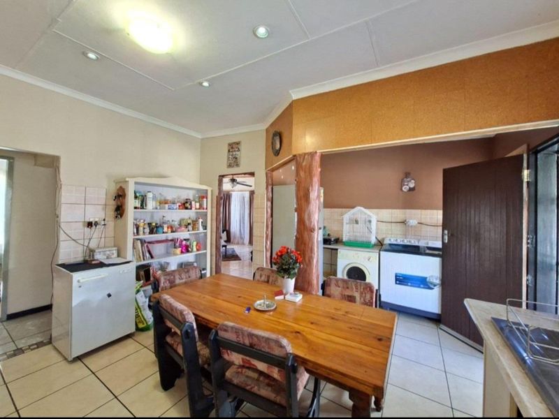Open plan dining and kitchen area featuring tiled flooring, recessed lighting, and functional built-in cabinetry with a tiled splashback.